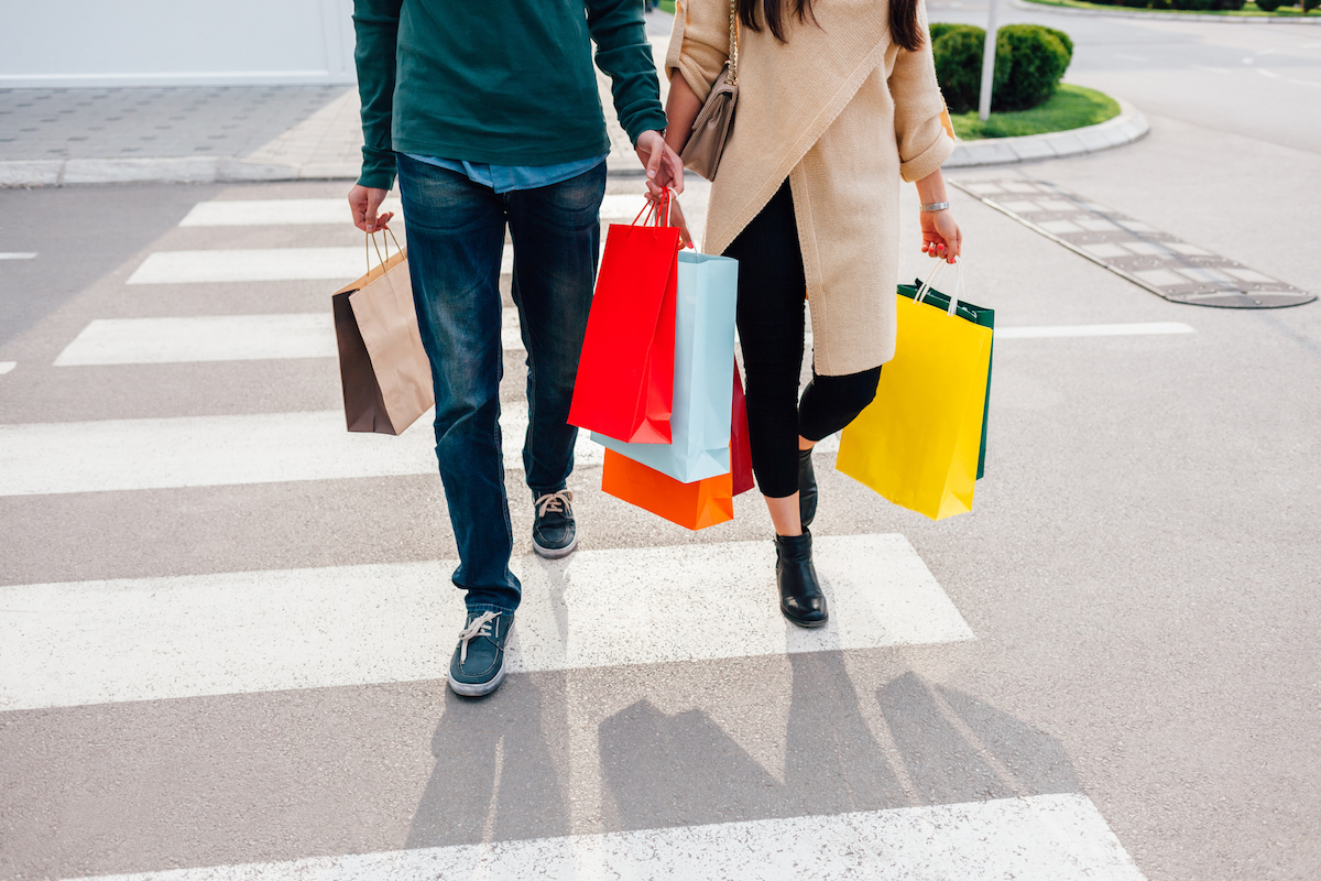 Closeup of couple crossing the street with shopping bags at sunset