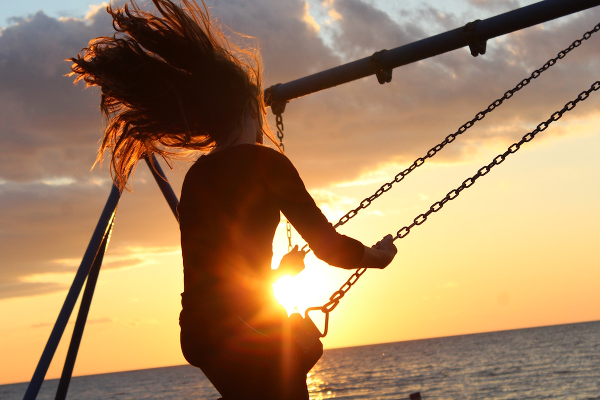 girl on a swing with sun in the background