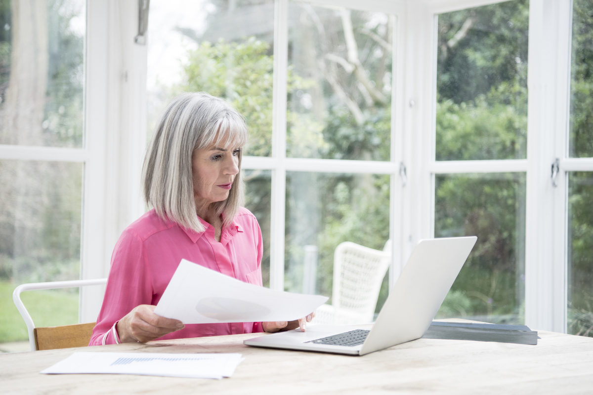 senior woman sitting at a desk holding papers