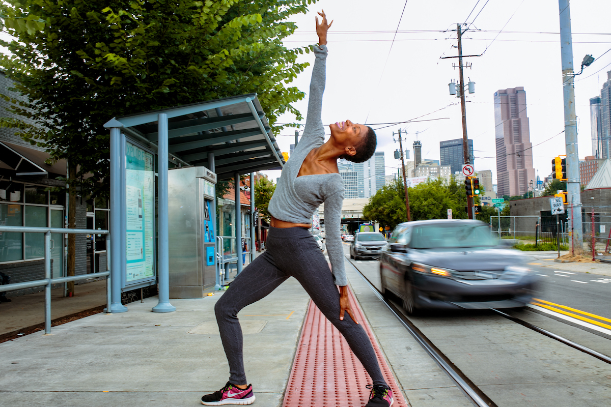 A woman holds a stretch pose on a city street.