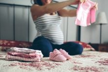 pregnant woman looking baby clothes