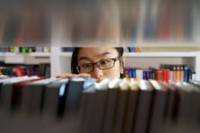 A woman looks through the selection of books at a library.
