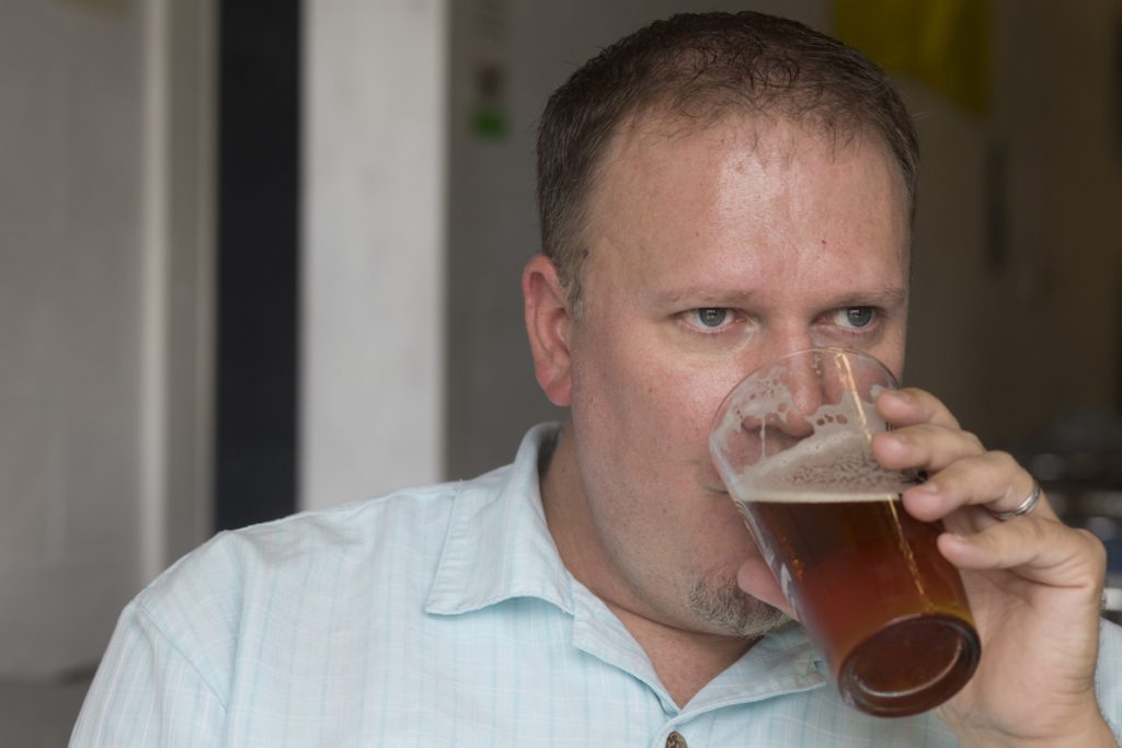Close up shot of a man drinking a tall glass of beer.