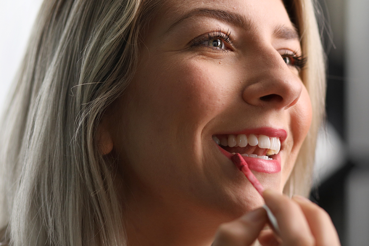 A woman puts lipstick on her lips