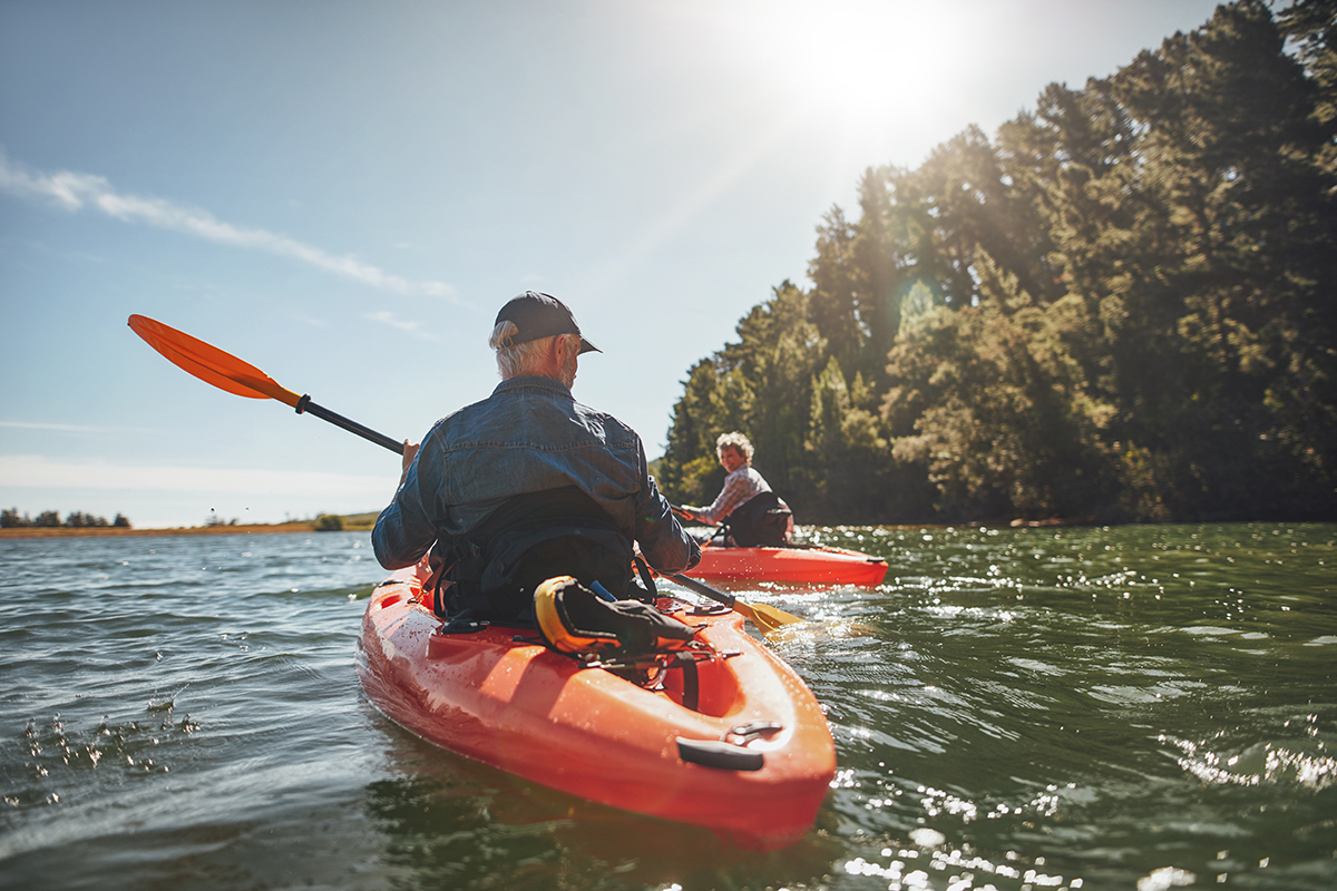 A retired couple go kayaking on a river.