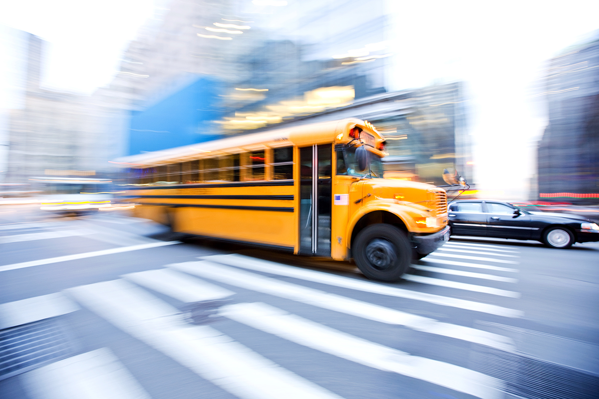 A school bus drives down a busy street.
