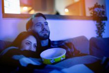 A couple snuggle as they watch TV.