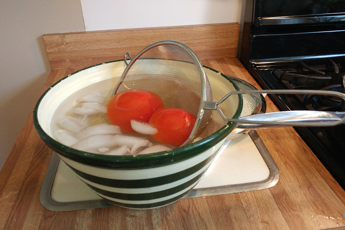 Allow the tomatoes to cool, then peel the skins off, starting from the “X” you cut earlier. Repeat the blanching and peeling process in small batches until all the tomatoes are peeled.
