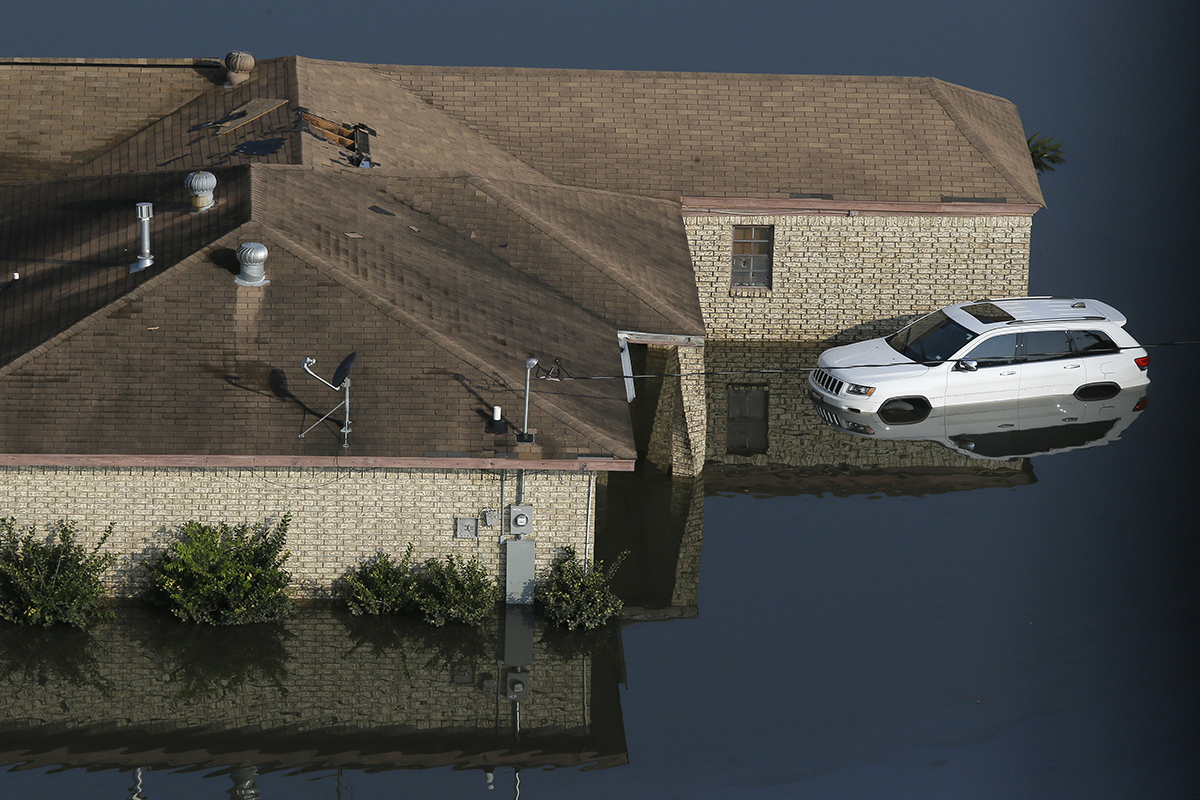 A flooded home with a hole cut in the roof sits in floodwaters caused Tropical Storm Harvey in Port Arthur, Texas on Friday, Sept. 1, 2017. AP Photo/LM Otero