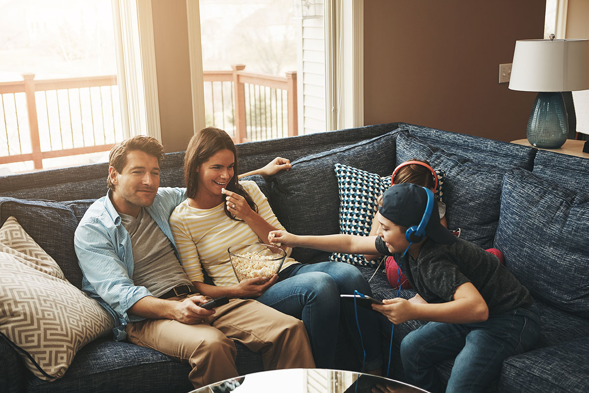 couple watching tv while their kids are busy using digital tablets at home