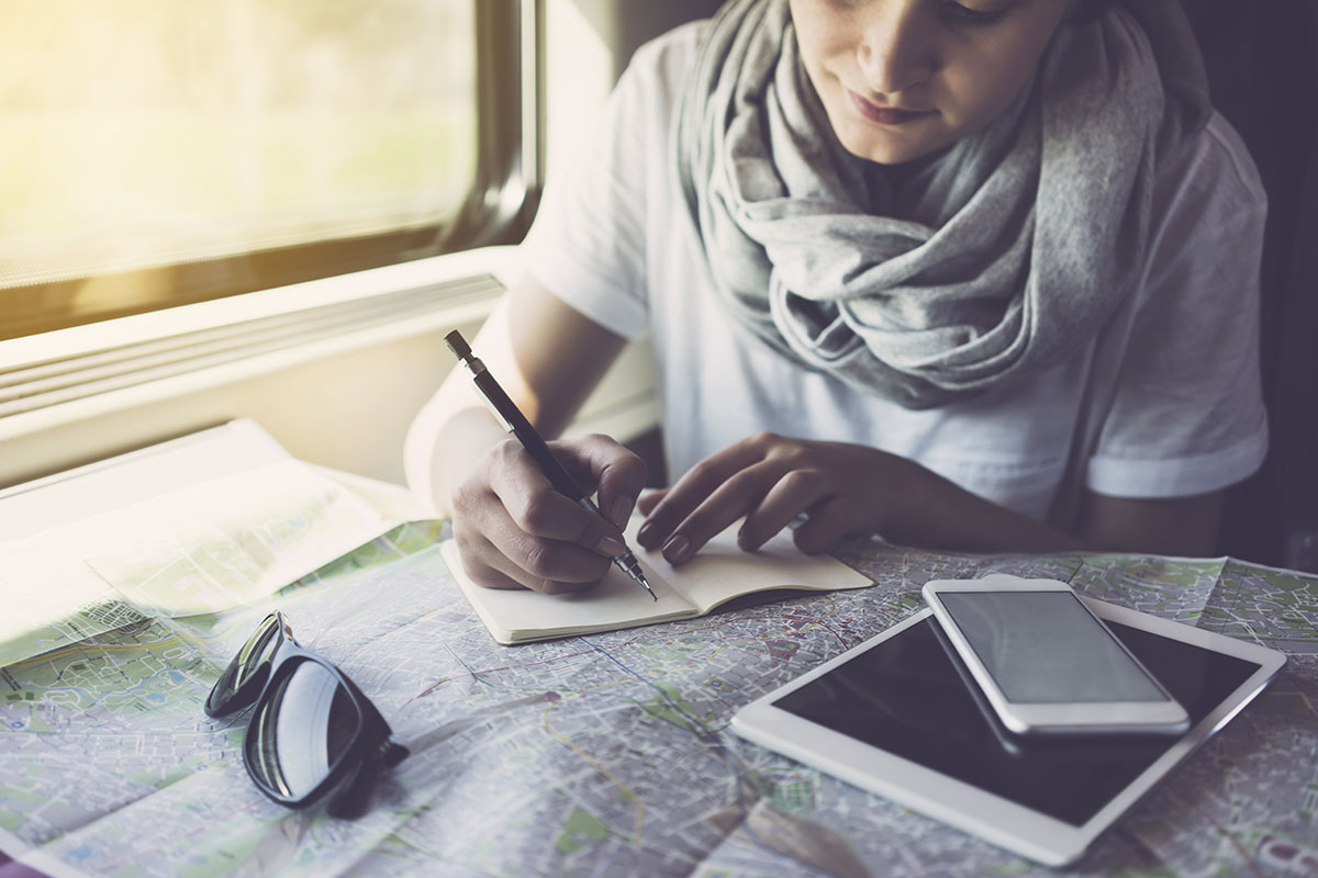 Young woman planning a trip, using smartphone, travelling by train