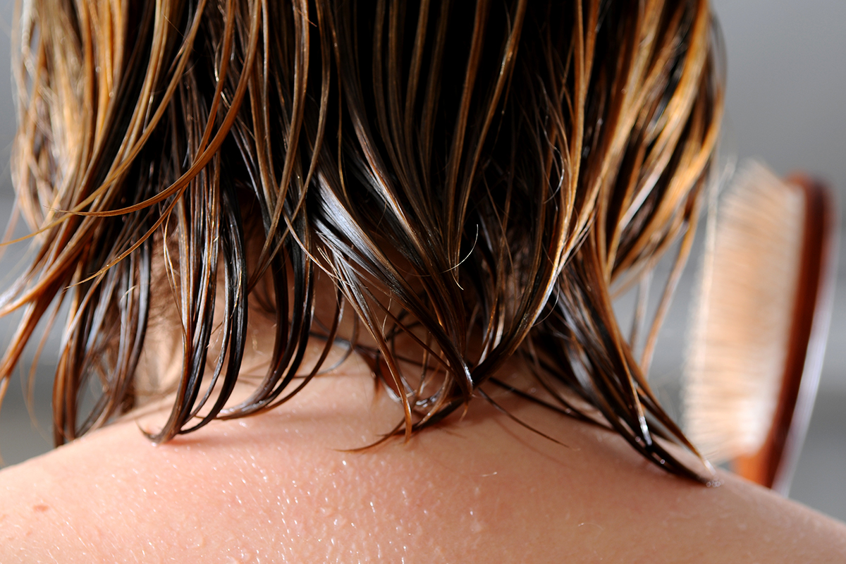 A person brushes their wet hair after taking a shower.