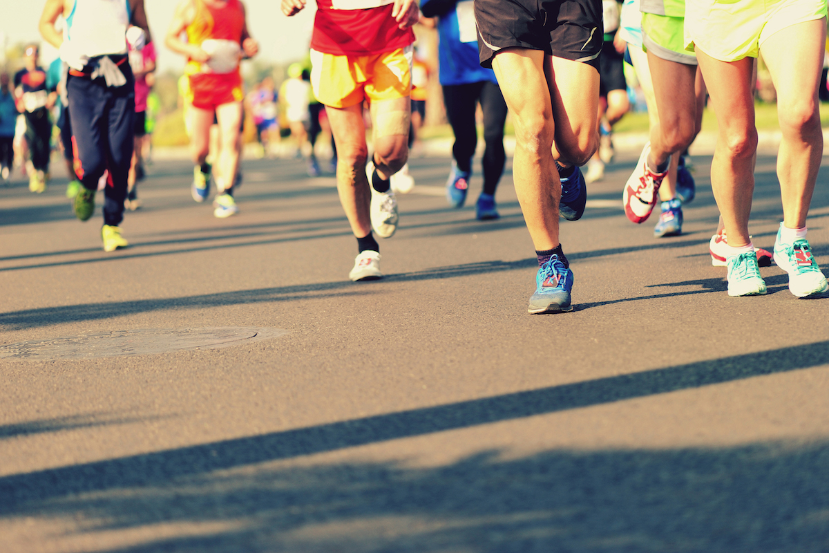 marathon athletes legs running on city road