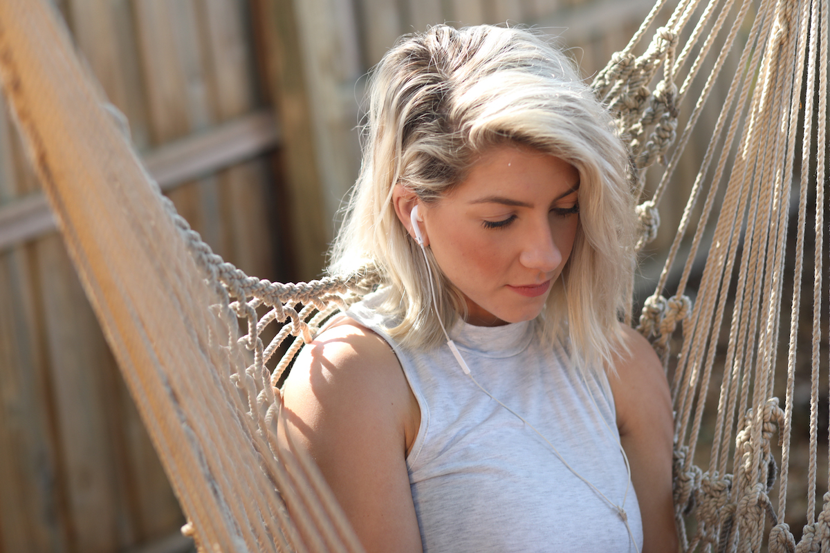A woman sitting in a hammock with earphones on