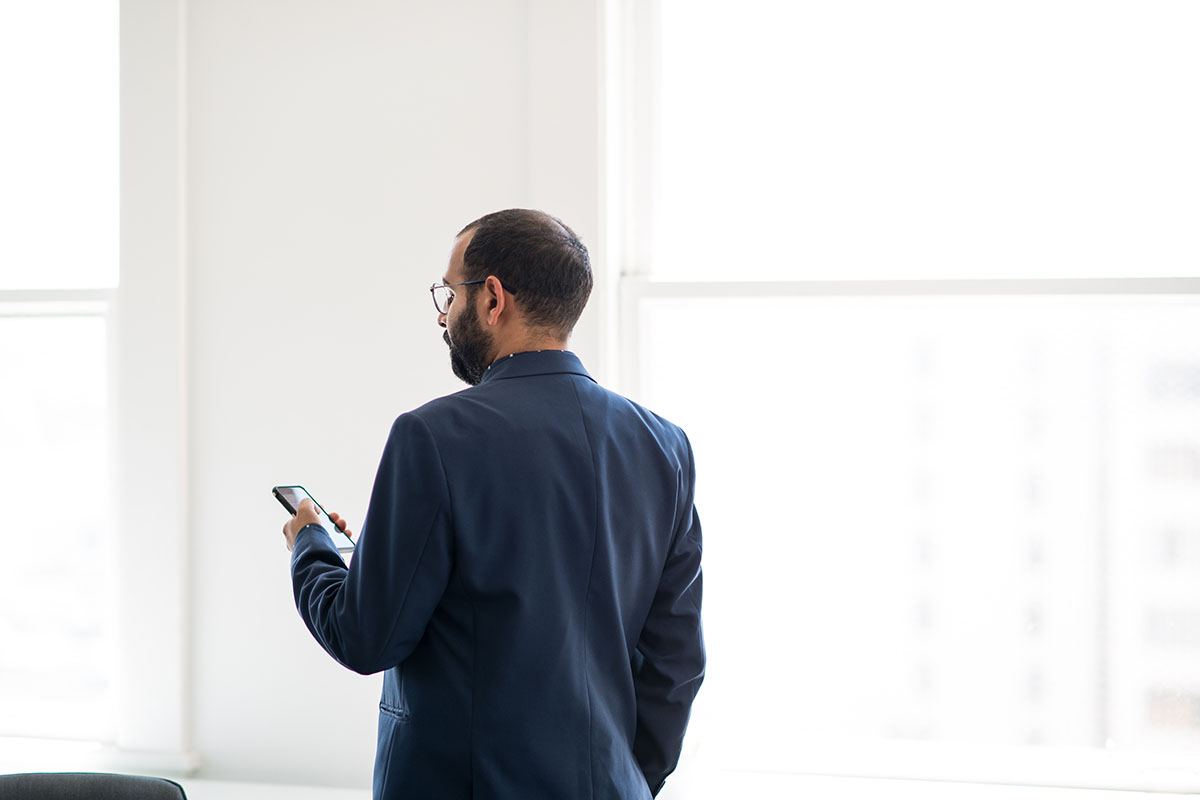 businessman wearing a blue suit looks at his smart phone