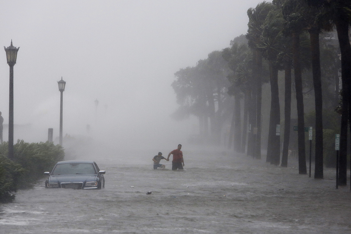 pedestrians walking by on a flooded street as Tropical Storm Irma hits Charleston, S.C.