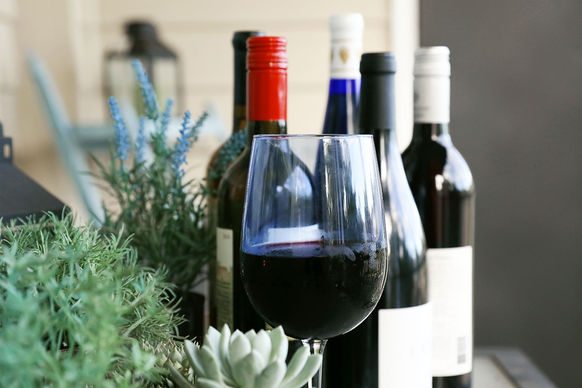 A glass of red wine with wine bottles.