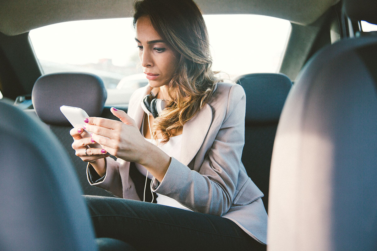 businesswoman in a taxi using smartphone.