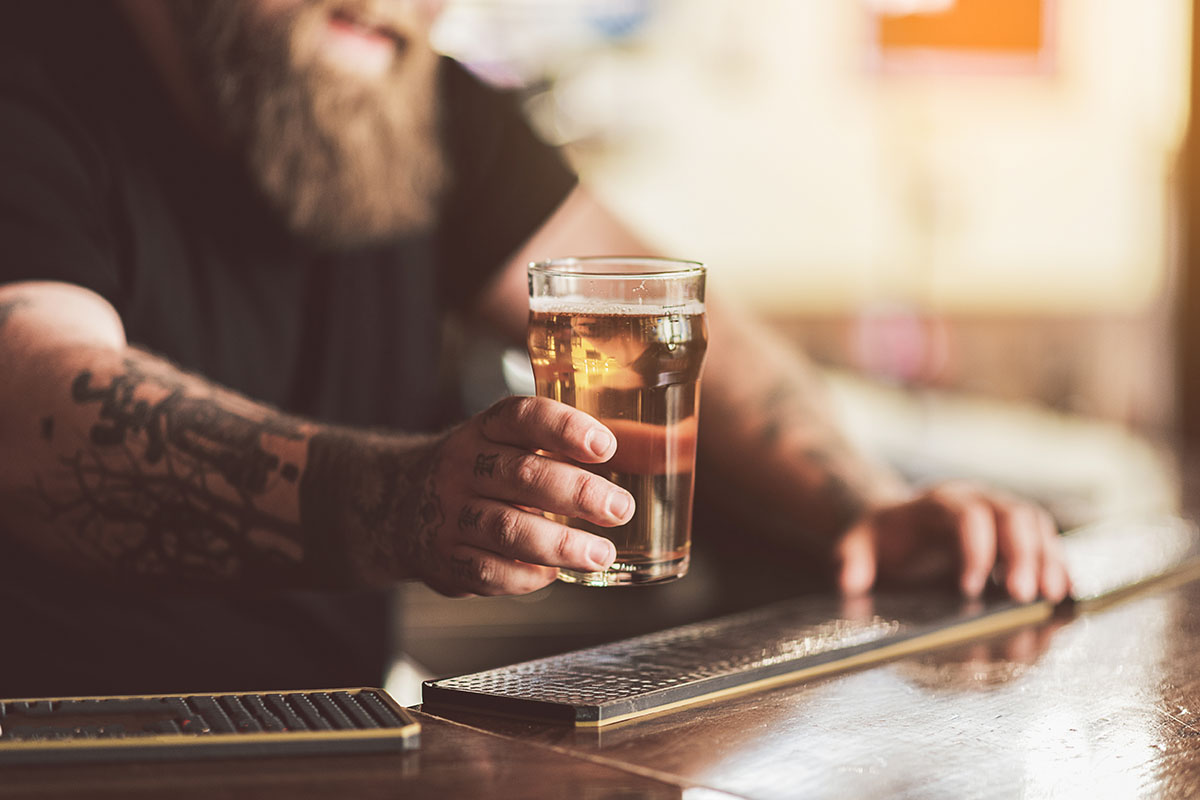 Close up of hand of man holding glass of cold beer