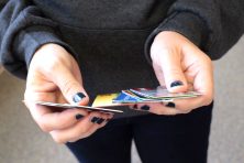 A detail photo of a woman's hands holding multiple credit cards.
