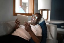 A woman laughs as she watches something on her iPad.