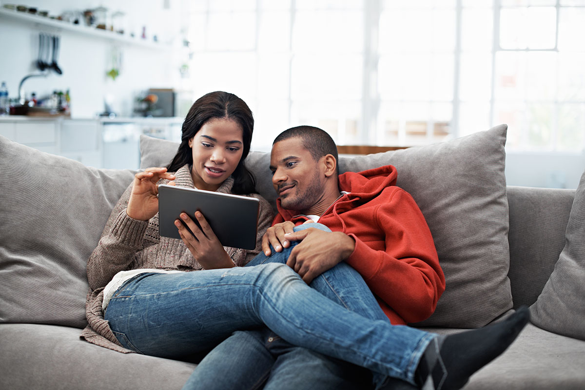 Cropped shot of a young couple using their tablet while sitting on the sofa at home