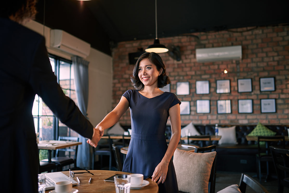 woman shaking hands with man in cafe for job interview