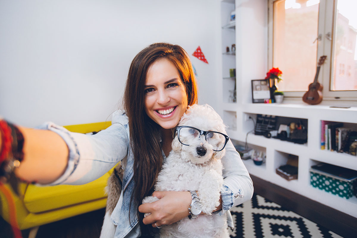 woman in her home taking a selfie while holding a dog