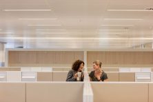 Businesswomen with coffee gossiping in office cubicles