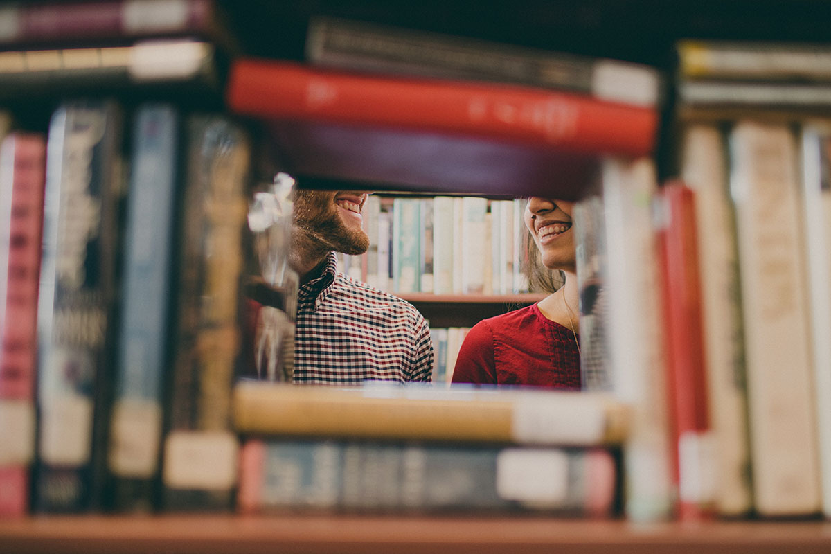 two people behind books in a library