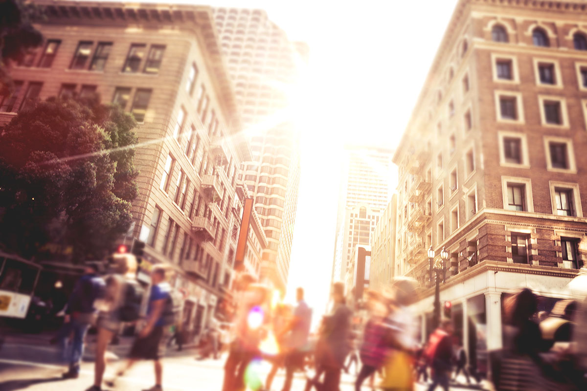 People walk down a busy street in a city.
