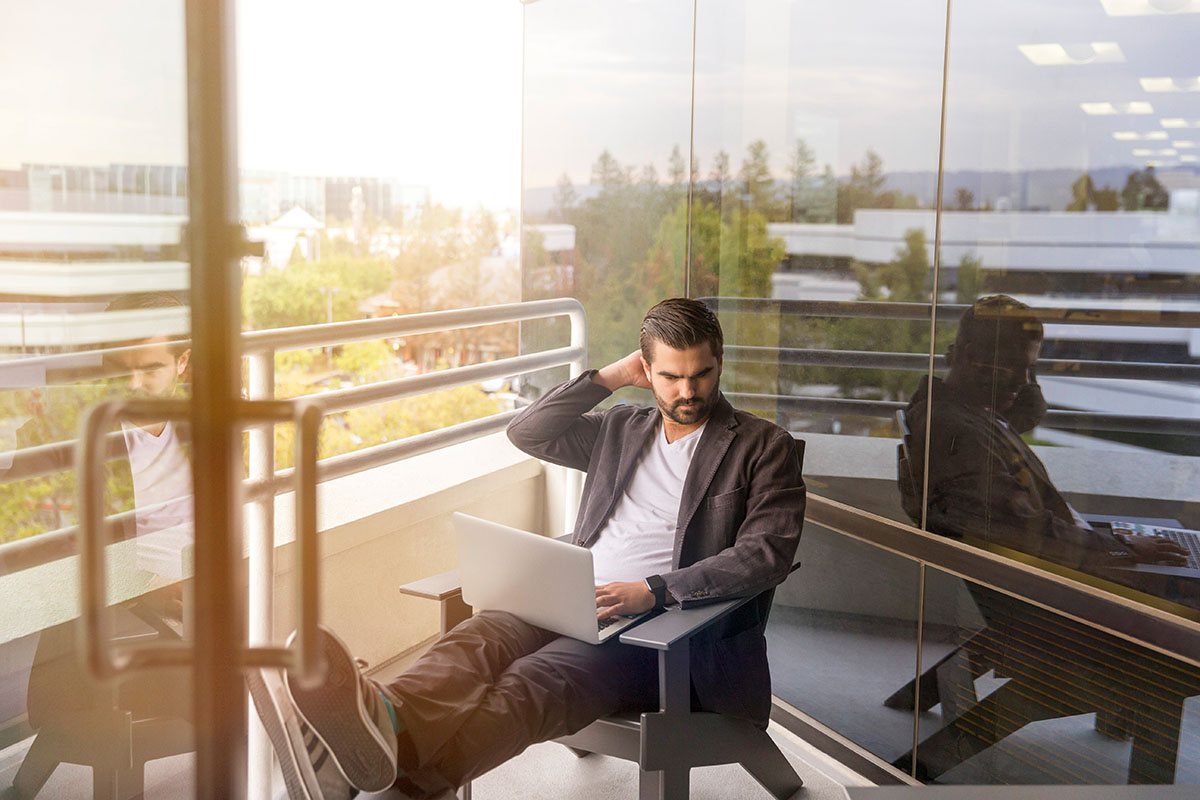 man working on laptop from balcony