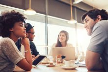 Portrait of group of young people sitting at a cafe and discussing work.