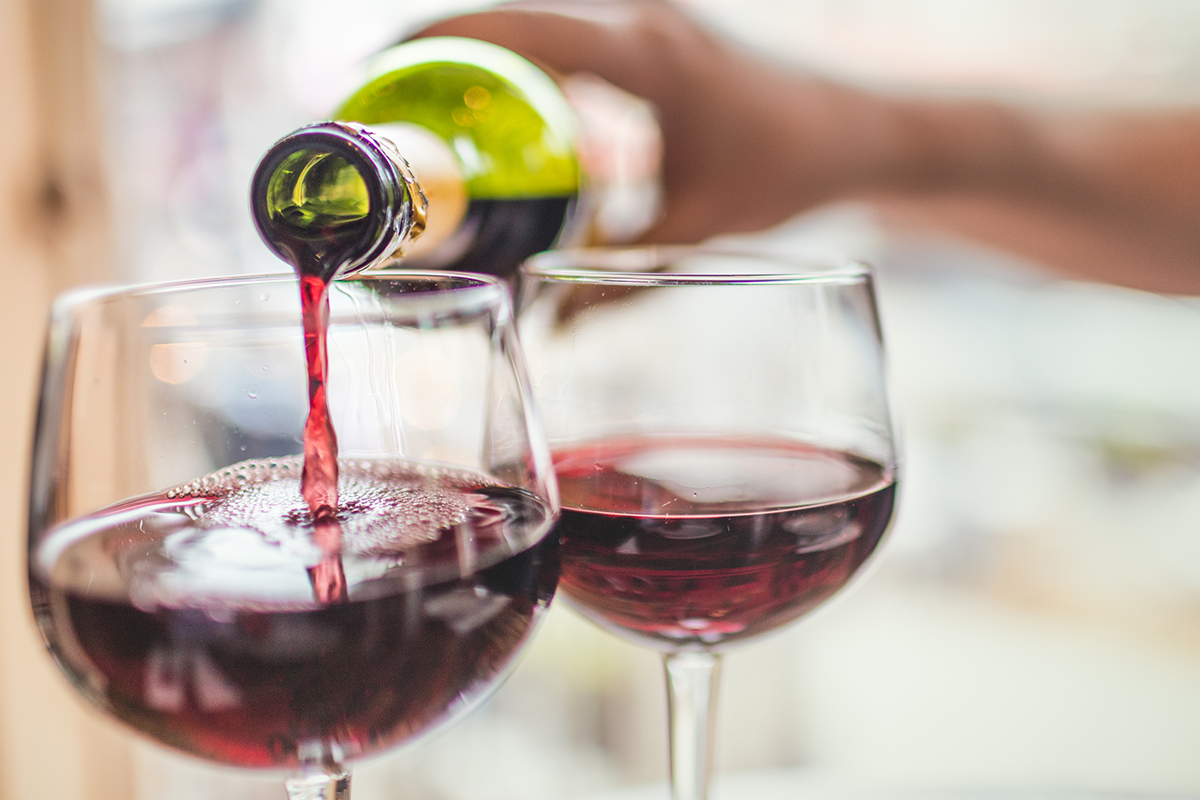 Two glasses of red wine are poured for customers at a restaurant.