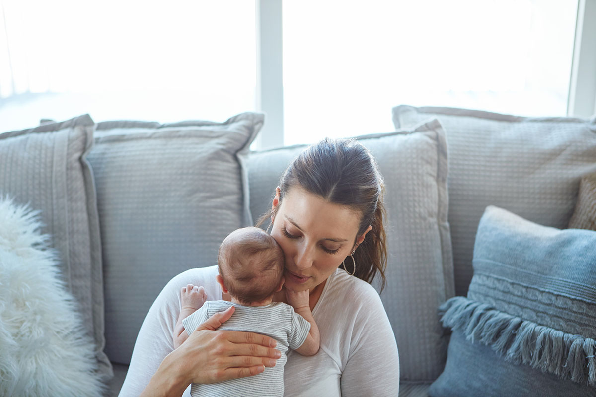 Shot of a mother sitting with her newborn baby on a couch