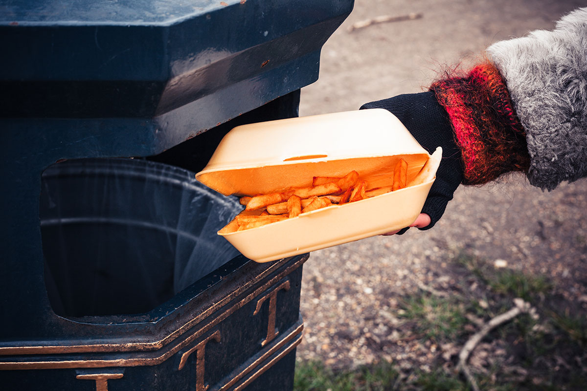 Closeup on a hand putting a box of chips in the bin