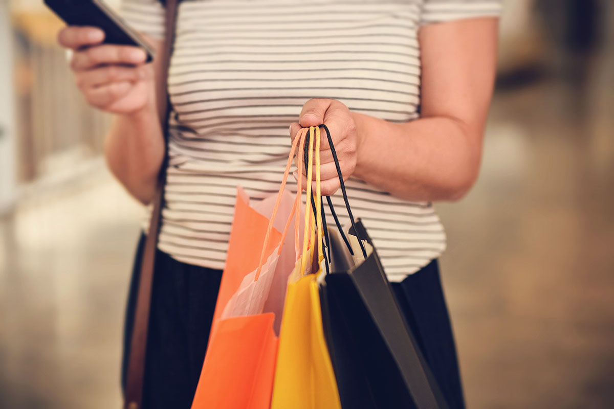 Young natural woman using a smartphone to shop in shopping mall.