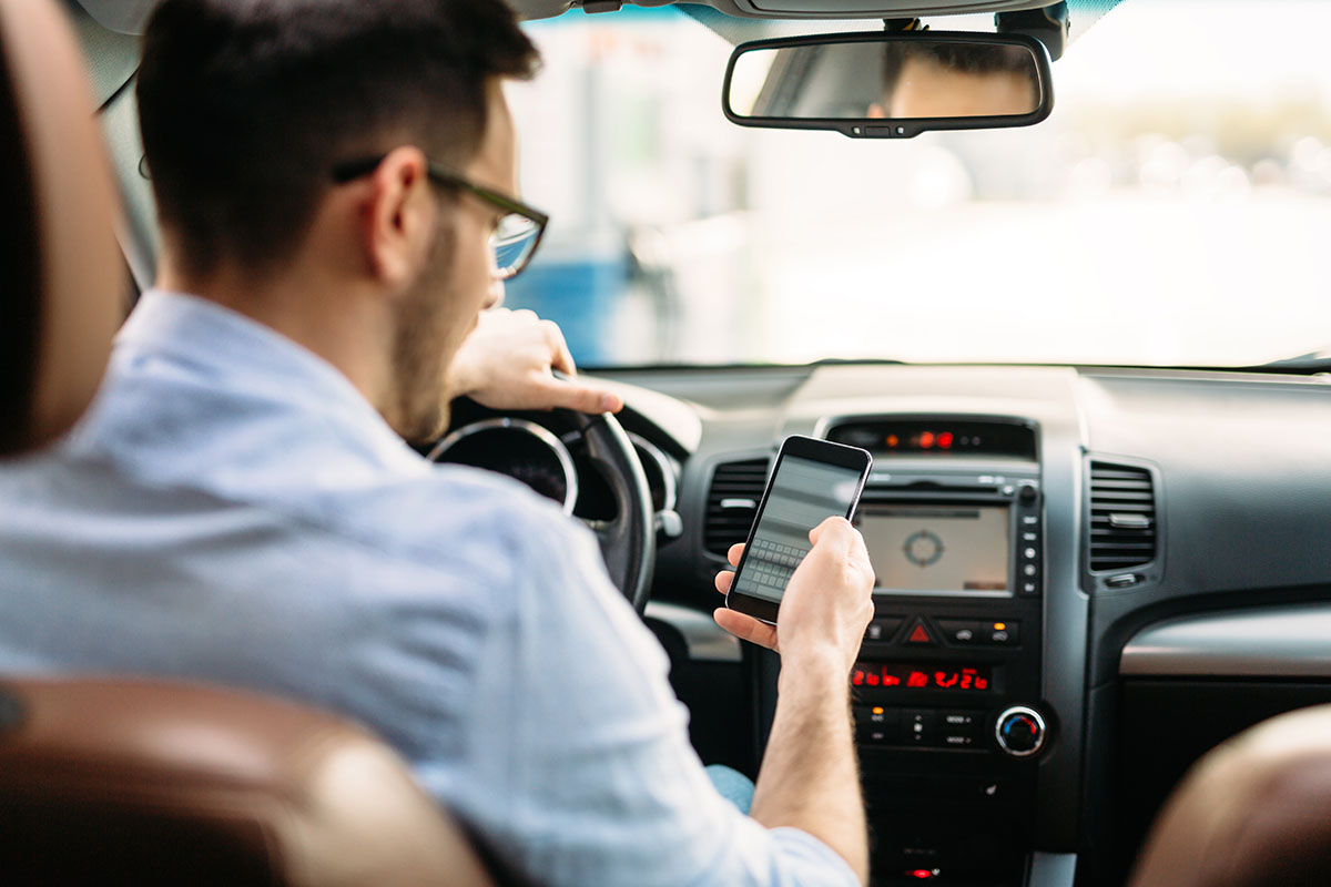 man using phone while driving the car