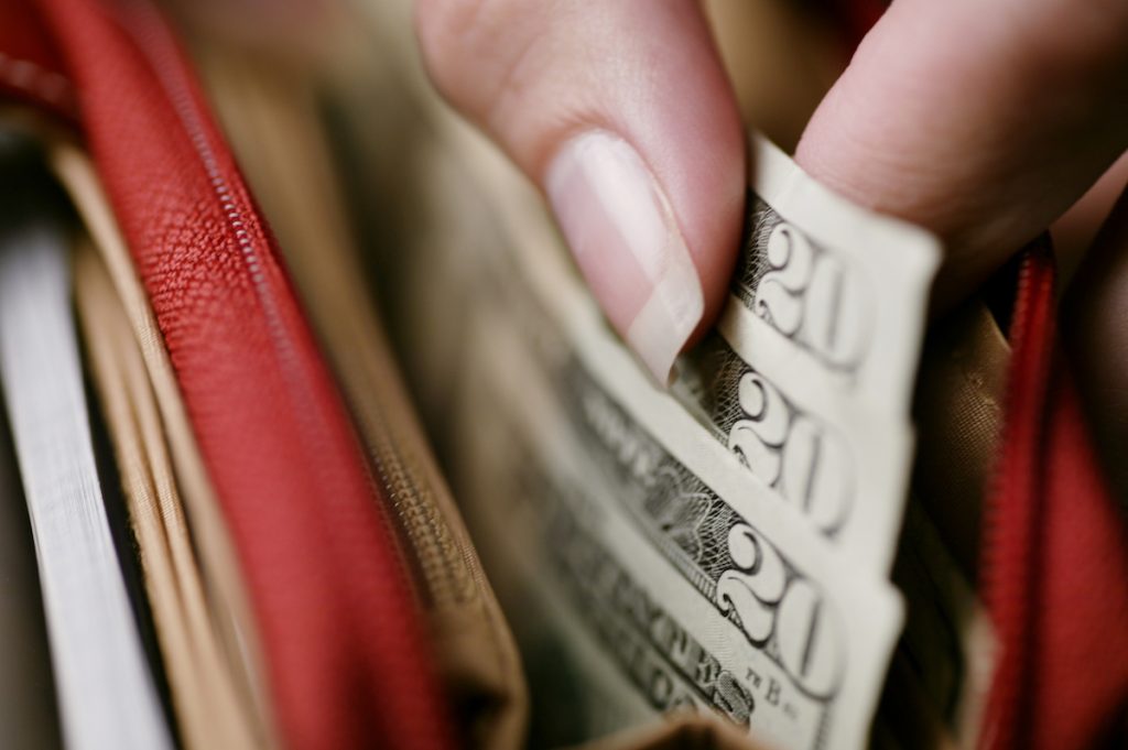 Woman's hand taking money out of wallet.