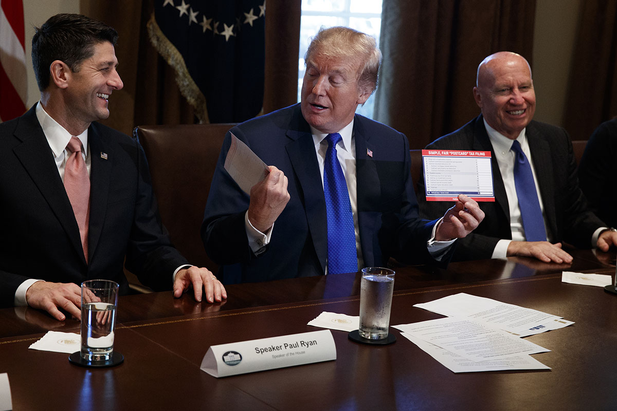 President Donald Trump holds an example of what a new tax form may look like during a meeting on tax policy
