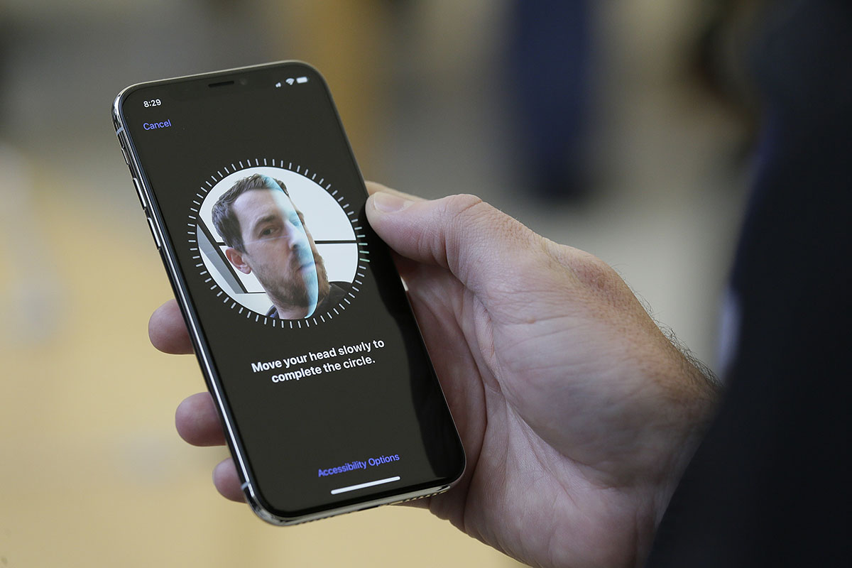 man holding iphone x using facial recognition