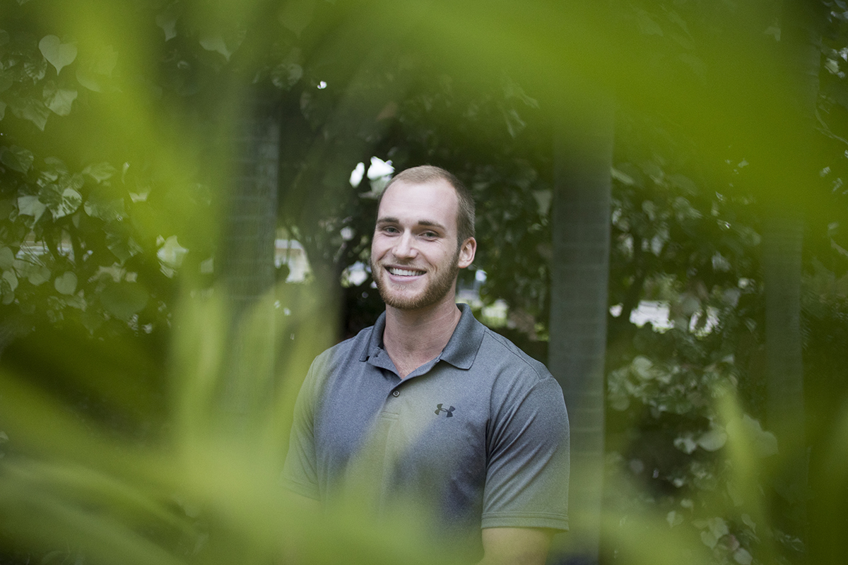 A man poses for a portrait in his parent's backyard garden.