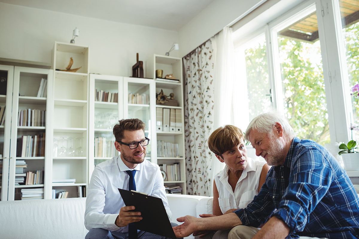 Senior couple planning their investments with financial advisor in living room