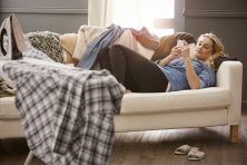 Young woman lying on the couch looking at her phone.
