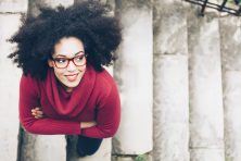 Portrait of smiling young woman standing arm crossed on staircase.