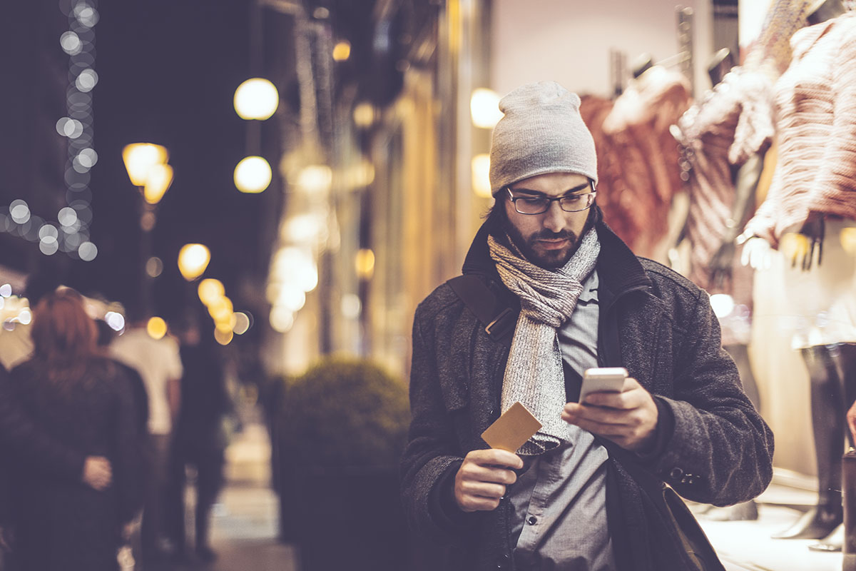 man checking credit card on smartphone while holiday shopping
