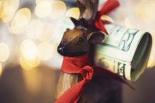 Rustic holiday deer with roll of dollars.