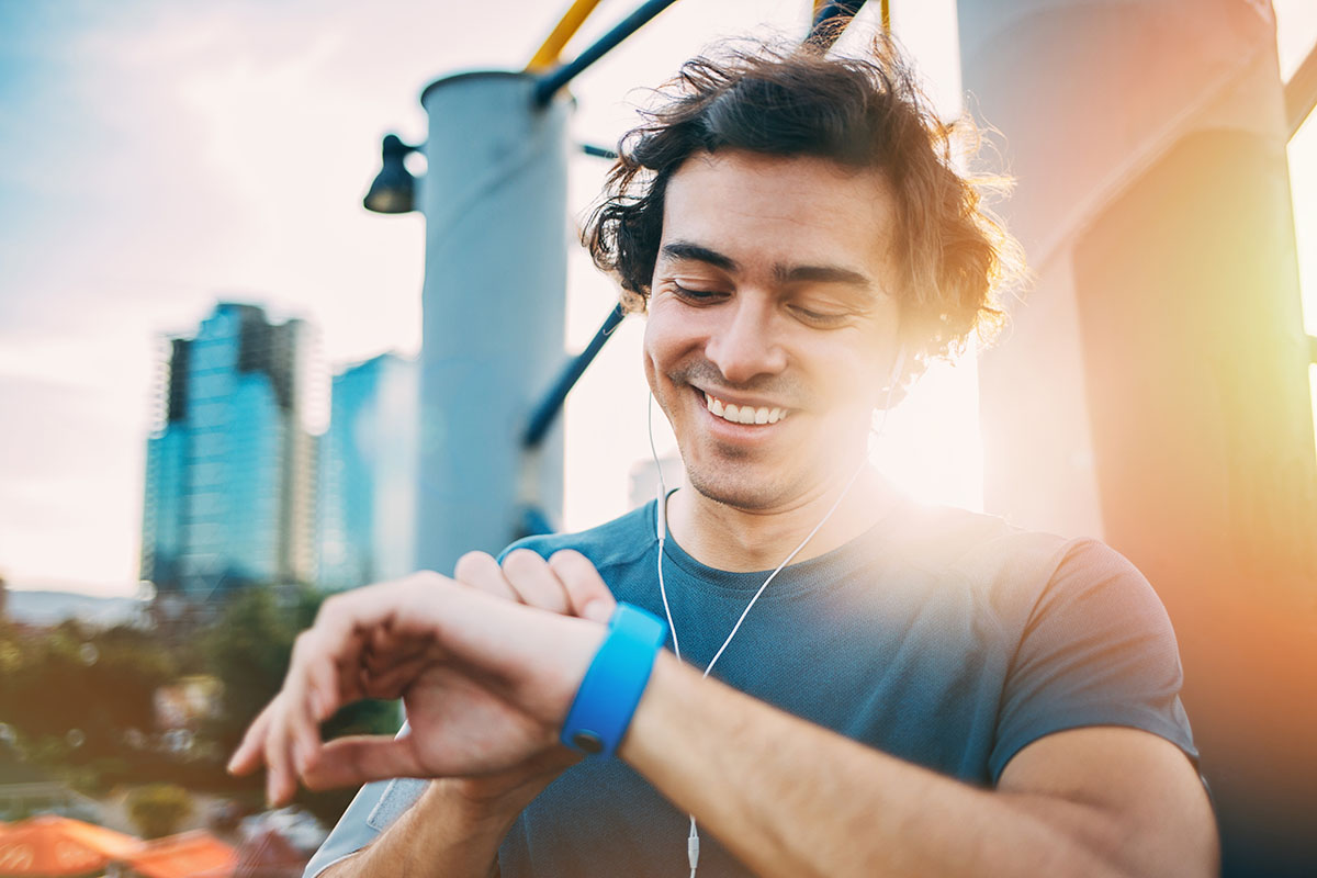 Young man in sports wear looking at his smart watch outdoors
