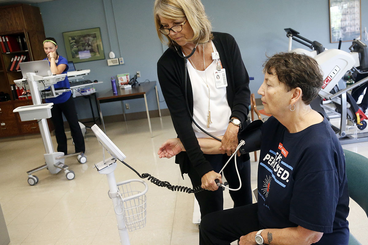 An older woman gets her blood pressure taken by a therapist.