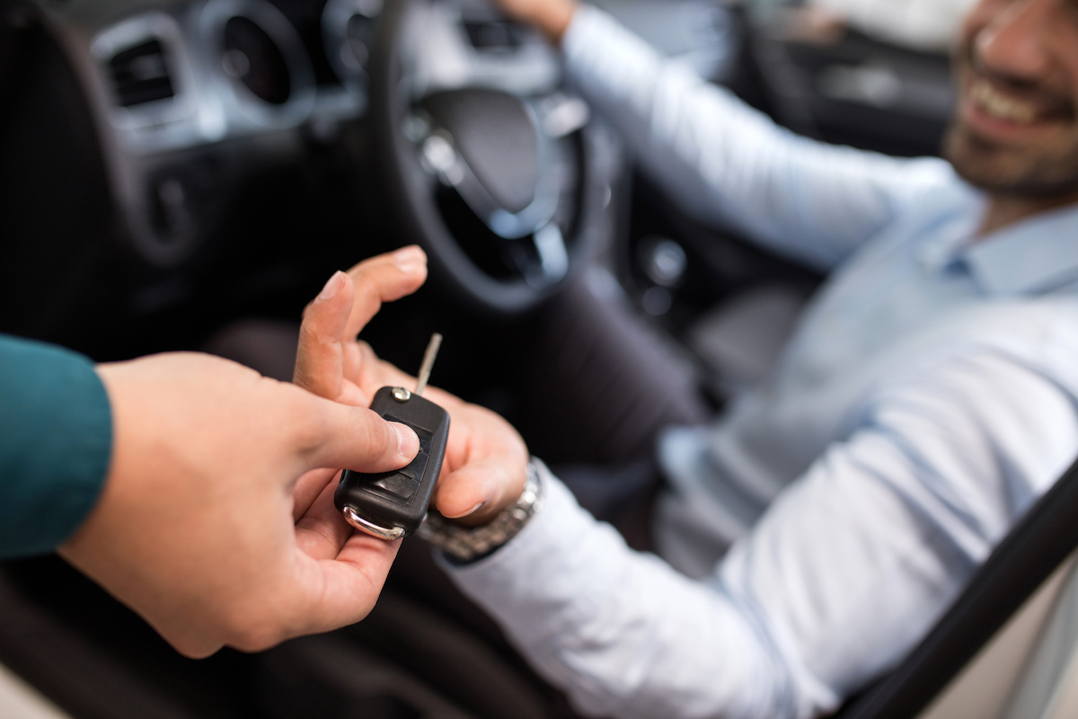 Close up of a man sitting in a car and receiving car keys